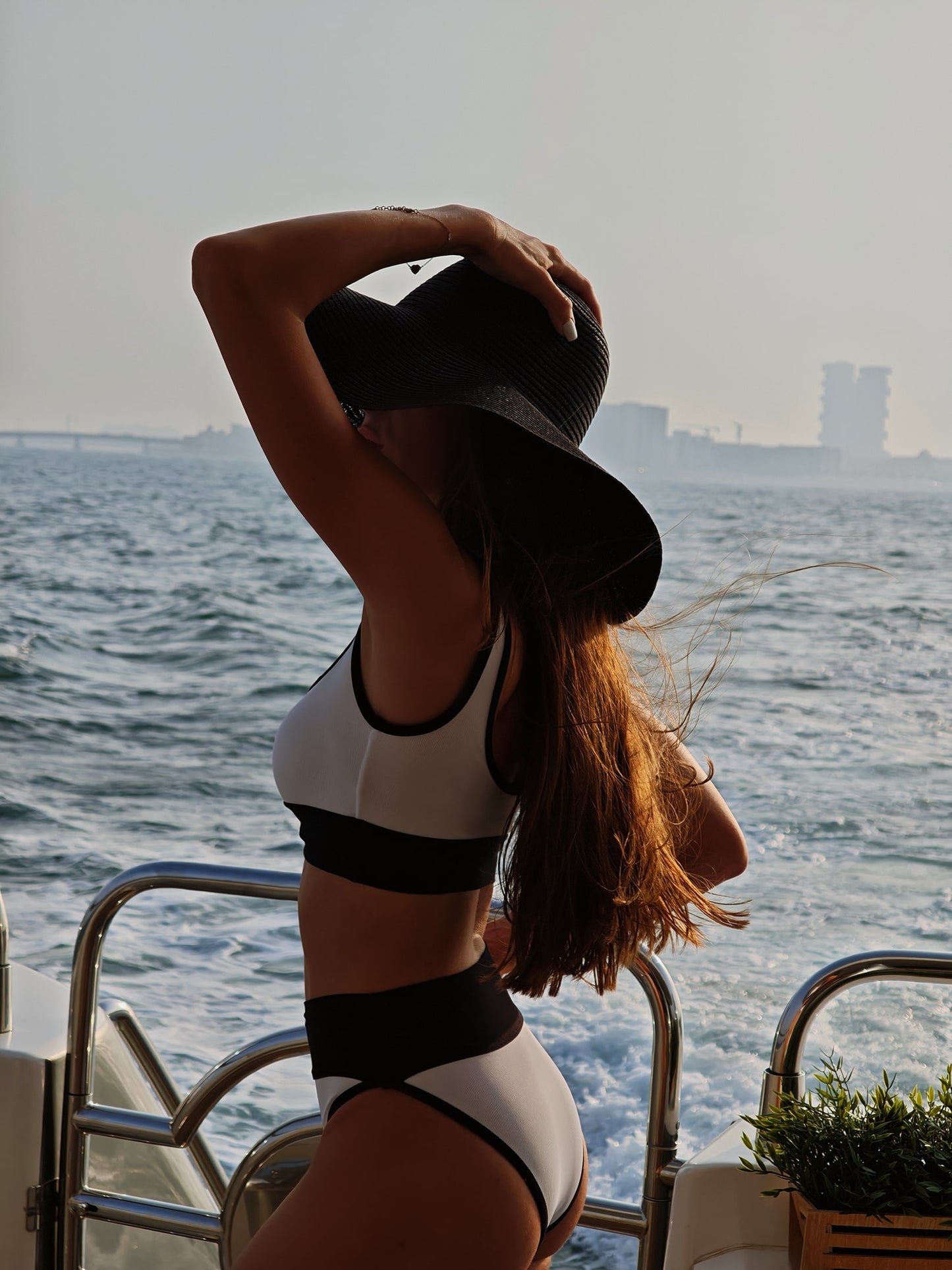 A woman wearing a stylish white and black bikini, standing confidently on a beach.
