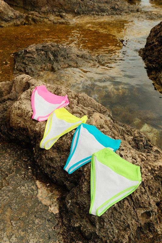 A bikini alongside a pair of white and yellow swimsuits displayed on a flat surface.