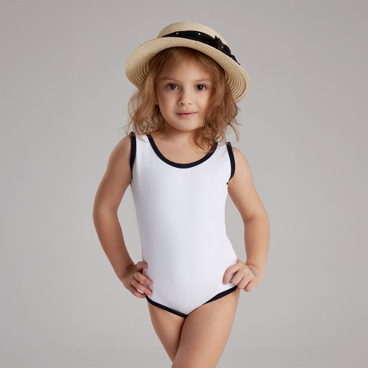 Young girl wearing a white one-piece swimsuit with black trim and a straw hat, posing confidently in studio setting.